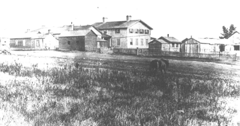 View of the back of the two-storey historic Fort Riley Hospital and surrounding buildings. (Image courtesy of Fort Riley, Conservation Branch)